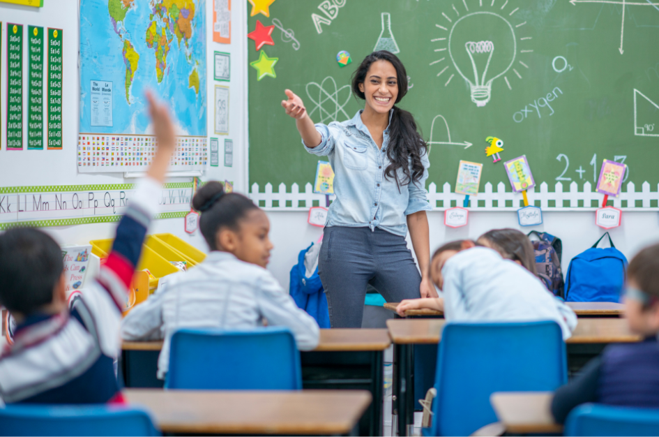 A teacher smiles as she teaches in front of her class.